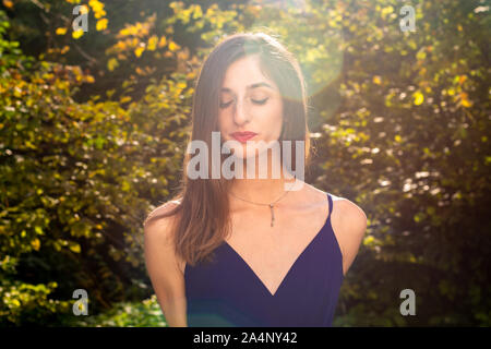 Junge Mädchen im blauen Kleid mit geschlossenen Augen Wald Hintergrund Stockfoto