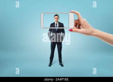 Der Geschäftsmann Gesicht im Fokus sehen durch den Rahmen der Telefon. Stockfoto