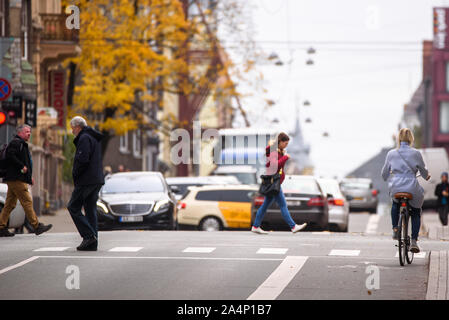 RIGA, Lettland. 15. Oktober, 2019. Dame auf dem Fahrrad wartet an Kreuzung zum grünen Licht, während die Fußgänger die Straße überqueren. Autos bewegen sich auf Ba Stockfoto