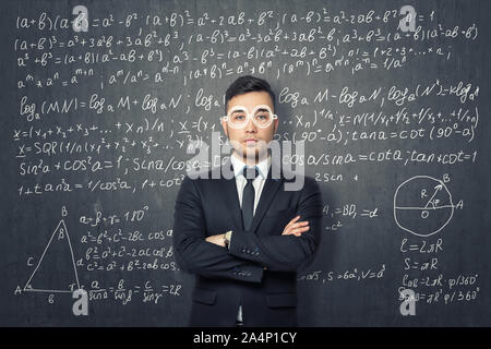 Unternehmer, die auf dem Hintergrund der Tafel mit mathematischen Formeln. Stockfoto