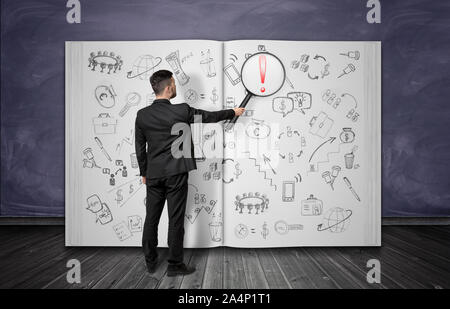 Geschäftsmann holding Lupe bei Giant Notebook mit viel Bleistift finanzielle Zeichnungen in Es Stockfoto