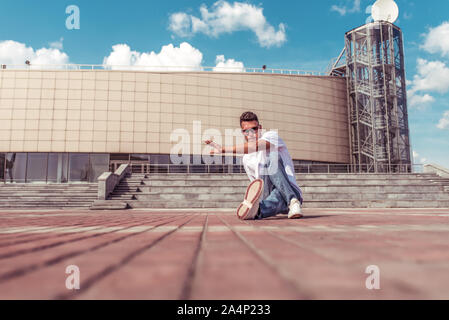 Tänzer tanzen Breakdance, Hip Hop. Stadt Sommer, Wolken Hintergrund. Aktive Jugend lifestyle junge männliche Tänzer fitness Bewegung workout breakdancer. In Stockfoto
