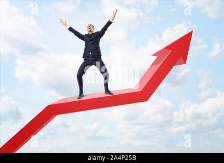 Geschäftsmann zum Ausdruck glücklich und auf Big Red Line Graph mit einem umgedrehten Pfeil Stockfoto