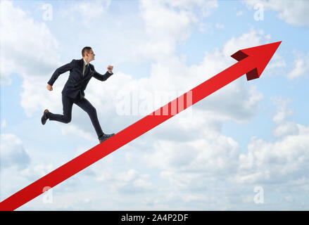 Unternehmer, die großen roten Pfeil auf dem Hintergrund der blauen Himmel. Stockfoto