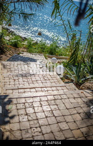 Eine Steintreppe führt durch einen Durchgang zum Meer Stockfoto