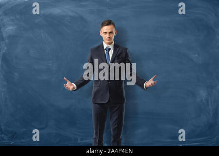 Erfolgreiche Unternehmer steht mit offenen Armen auf der blauen Tafel Hintergrund isoliert Stockfoto