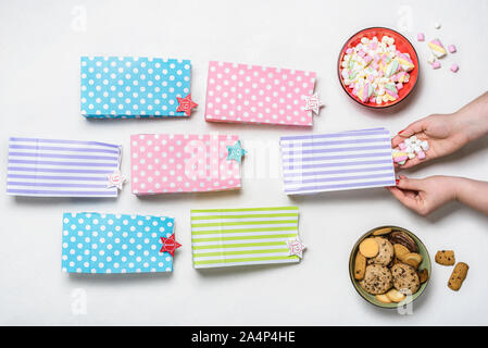 Handgefertigte Weihnachten Adventskalender Konzept. Füllen Adventskalender Geschenk Taschen mit Marshmallows und Xmas Cookies. Bunte Papierbeutel und Zahlen. Stockfoto