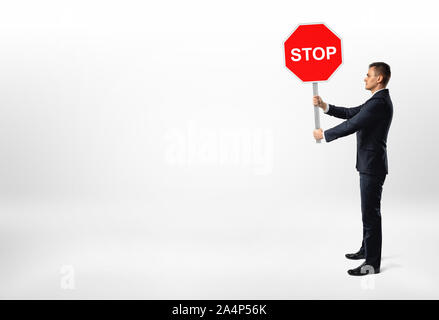 Unternehmer stehen auf weißem Hintergrund und mit einem Stoppschild. Stockfoto