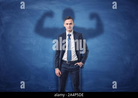 Geschäftsmann wirft Schatten von großen, kräftigen muskulösen Mann seinen Bizeps angezeigt. Stockfoto