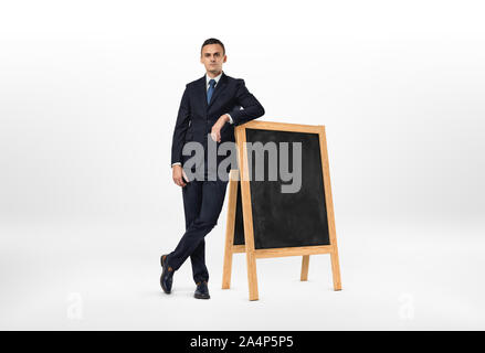 Geschäftsmann mit einem ernsten Gesicht lehnte sich auf der kleinen Tafel Stockfoto