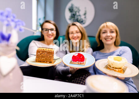 Frauen Freunde auf Kamera, smilikng, Kuchen, drei Freundinnen im Cafe Kaffee trinken und essen Desserts, Frauen während der Mittagszeit Stockfoto