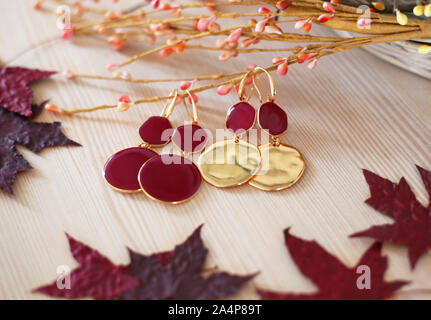 Goldene Ohrringe mit roten Steinen und rote Blätter im Herbst Dekor Stockfoto