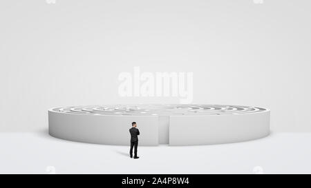 Ein kleiner Geschäftsmann stand vor einer großen weißen runden Labyrinth direkt neben dem Eingang. Stockfoto