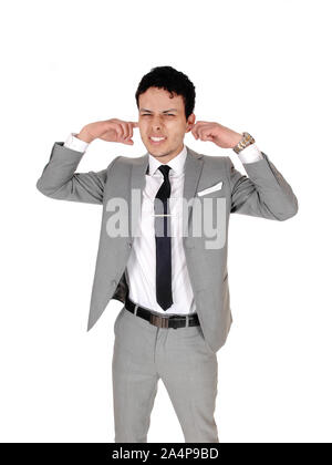 Junge zornige Mann, der mit seinem Finger in die Ohren, über den Lärm, auf weißem Hintergrund Beschweren Stockfoto