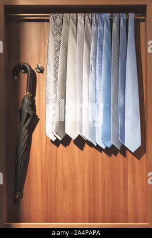 Krawatte und Schirm im Schrank. Eine Vielzahl von Krawatten, die in Herren gehängt sind Stockfoto