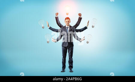 Ein Geschäftsmann mit viele Hände von Glühbirnen umgeben mit einem von Ihnen beleuchtet. Stockfoto
