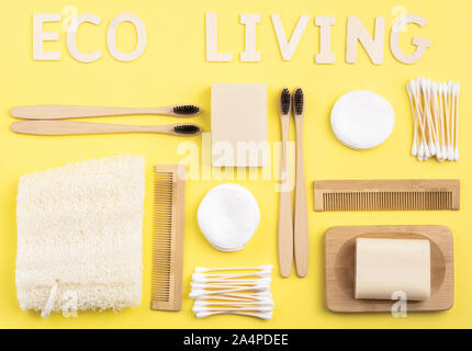 Eco lebendiges Konzept. Biologisch abbaubare Bambus Zahnbürsten, handgemachten Verpackung Seife und Shampoo Bars, Wattestäbchen Pads, luffa auf gelbem Hintergrund, Ansicht von oben, selektiver Fokus Stockfoto