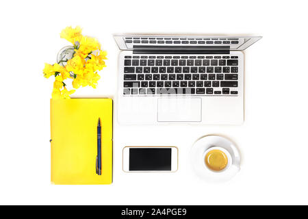 Arbeitsbereich mit Laptop, Tasse Kaffee, Mobiltelefon, Kopfhörer und gelbe Blume, Notizbuch mit Stift auf weißem Hintergrund, isoliert. Ansicht von oben. Flach. Konzept online einkaufen. Stockfoto