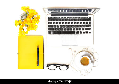 Arbeitsbereich mit Laptop, Notebook, Mode Gläser, Tasse Kaffee, Kopfhörer und gelbe Blumen auf weißem Hintergrund, isoliert. Ansicht von oben. Flach. Konzept online einkaufen. Stockfoto