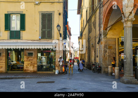 Blick vom historischen Zentrum der berühmten Stadt Pisa mit Afrikanischer straßenhändler an der Ecke einer engen Gasse im Sommer, Toskana, Italien Stockfoto