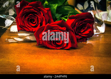 Blumenstrauß aus roten Rosen auf einem Holztisch Hintergrund in einem Café. Rote Rosen auf Holz- Hintergrund. Stockfoto