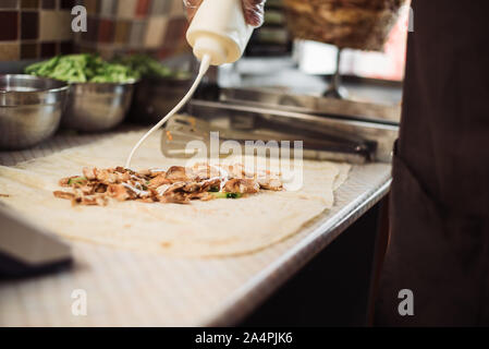 Kochen fajitos im Cafe. Kochen shawarma in Pita in der Küche. Wrap Chicken, Karotten, Salat, Tomaten in pita Brot. Stockfoto