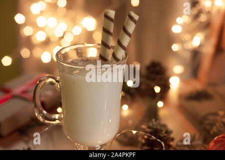 Traditionelle weihnachtliche Getränk Eierlikör mit Süßigkeiten und Gewürzen. Ansicht von oben. Selektive konzentrieren. Verschwommen Lichterketten. Stockfoto