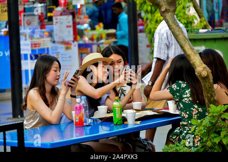 Singapur - 5. Oktober 2019: Gruppe von jungen asiatischen Frauen in einem Café in Little India, Singapur sitzen, entspannen und mit Smartphones Stockfoto