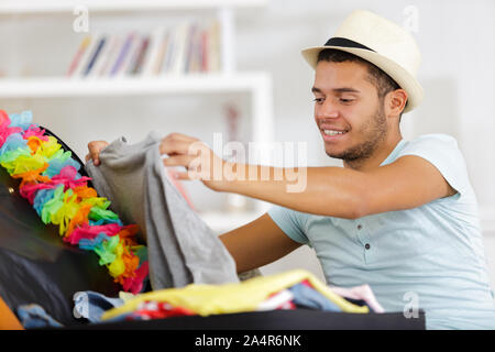 Mann Verpackung Gepäck auf dem Bett für Reisen Stockfoto