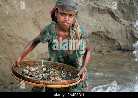 Ein junges Mädchen siebt Steine und Kiesel aus Sand mit einem Bambus Sieb, in einem Steinbruch auf der Bank von Dauki Fluss, in Sylhet, Bangladesh. 18. Januar 2010. Stockfoto