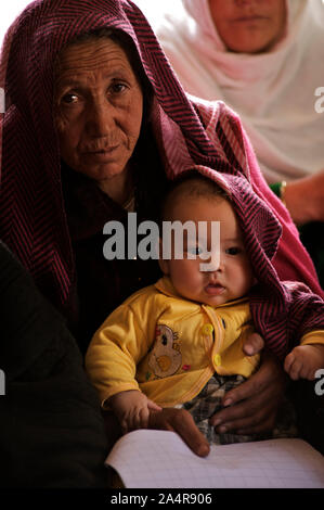 Eine ältere Frau mit einem Kind besucht die monatlichen Dorf Gesundheit Sitzung des Ausschusses, in der Ortschaft Surkhjoi, in Fuladi Tal, Provinz Bamyan, Afghanistan. 11. Mai 2009. Stockfoto