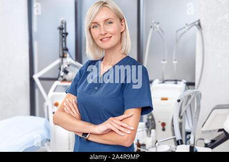 Kosmetologie Service. Junger Arzt stehen gekreuzte Arme zuversichtlich Close-up unter Beauty Klinik Stockfoto