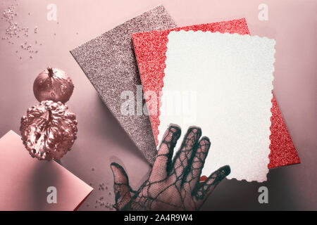 Kreative rosa, rot und grau getönten Halloween mockup mit Hand in Schwarz mesh Handschuh, schwebenden Stack von glitzernden Papier und dekorative Kürbisse bemalt Stockfoto