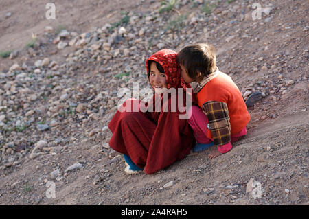 Zwei afghanische Mädchen spielerisch nach unten schieben, einem Hügel im Dorf der RAG-e-Shad, am Stadtrand von Bamian Stadt, Provinz Bamyan, Afghanistan. 11. Mai 2011. Stockfoto