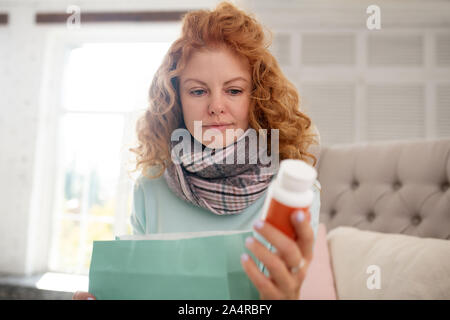 Rothaarige junge Frau lesen Rezept für Medikamente Stockfoto