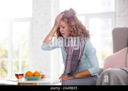 Frau berühren ihre Stirn, während sich benommen in Grippe Stockfoto