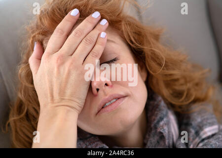 Rothaarige hübsche junge Frau in schreckliche Kopfschmerzen Stockfoto