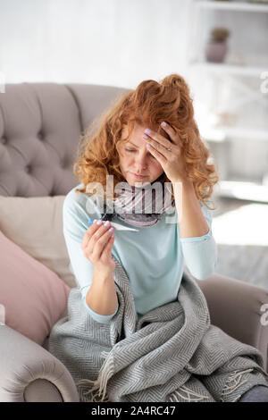 Rothaarige Frau Gefühl verärgert nach Messung der Körpertemperatur Stockfoto