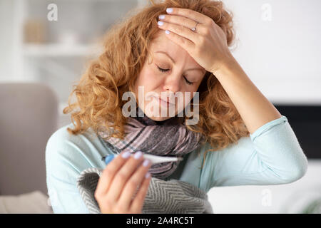 Frau Gefühl schrecklich während ihrer Stirn berühren und Fieber Stockfoto