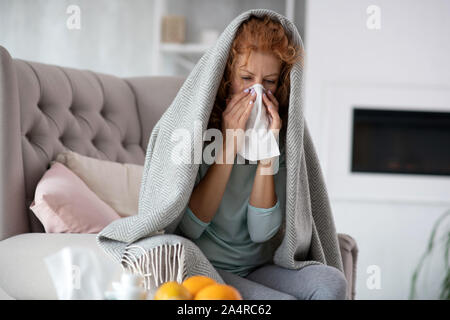 Rothaarige Frau mit Serviette, während in Sachen Nase Stockfoto