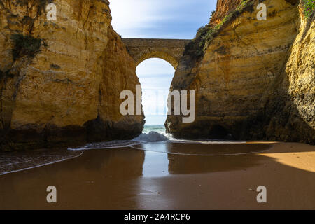 Die malerische Römische Brücke in Lagos zwischen den Felsen über dem Strand, Algarve, Portugal Stockfoto