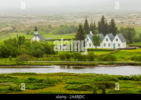 Tingvellir Kirche am Fluss Ufer zusammen mit weißen Häusern, Tingvellir National Park, Island Stockfoto