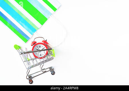 Rote Uhr, Warenkorb und Papiertüte auf isolierten weißen backgroun. Der Mangel an Zeit, Zeitverschwendung, Einkauf, einkaufen Konzept, Business Konzept.