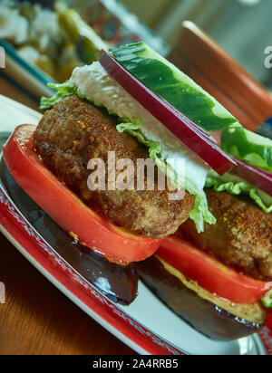 Griechische Lamm Burger, gekrönt mit Tzatziki, Feta, Tomaten, roten Zwiebeln, und geschreddert Kopfsalat Stockfoto