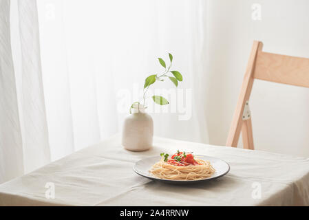 Handgemachte Pasta mit Ragout Soße auf Platte auf Vintage White Tisch mit Sieb und Blumen Stockfoto