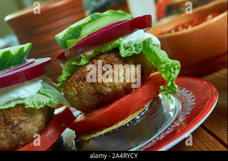 Griechische Lamm Burger, gekrönt mit Tzatziki, Feta, Tomaten, roten Zwiebeln, und geschreddert Kopfsalat Stockfoto