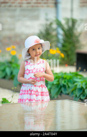 Adorable kleine Mädchen mit weißen Hut auf warmen und sonnigen Sommer Tag Stockfoto