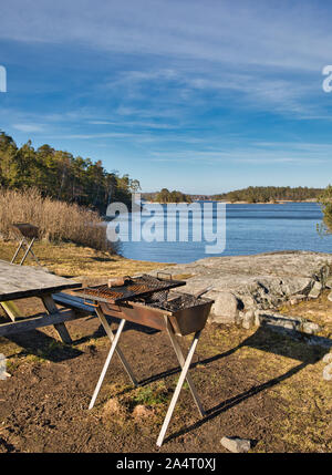 Rostender Grillgrill und Picknicktisch aus Holz am See, Bjorno Naturreservat (Bjorno Naturreservat), Stockholmer Archipel, Schweden Stockfoto