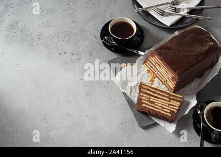 Dessert Rezept Konzept mit Kekstorte rohe Schokolade Kuchen mit Schichten von ganzen Kekse im Inneren. Mit zwei Tassen schwarzen Kaffee serviert und gesehen ov Stockfoto