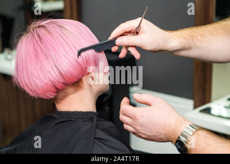 Der Friseur ist rosa Haare kämmen des Kunden in einen Friseursalon. Weibliche Client erhält an der Friseur gekämmt. Frau Haarschnitt. Schneiden. Stockfoto